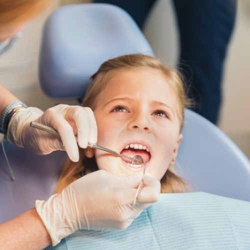 Dentists with a patient during a dental intervention to girl.